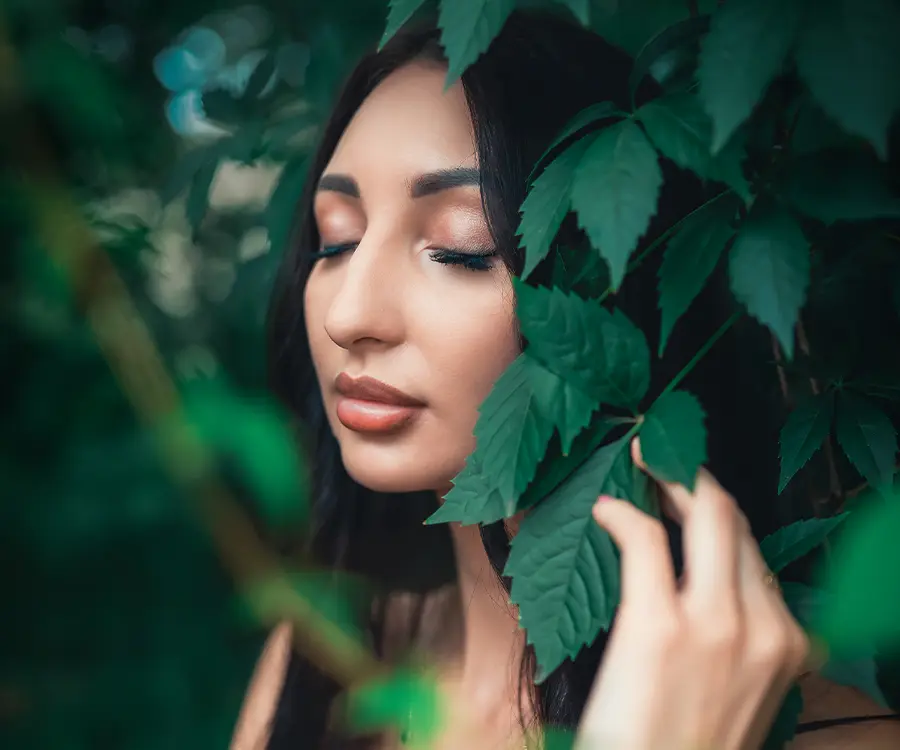 Zdjęcie kobiecej twarzy pośród liści drzew