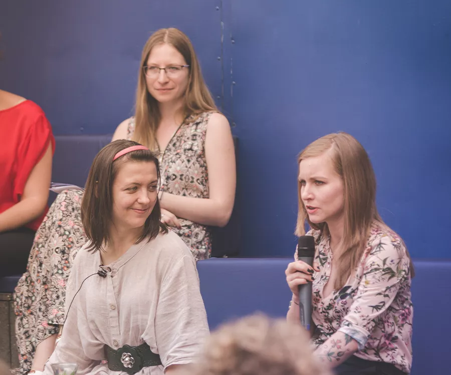 Fotografia eventowa ze spotkania autorskiego z Dorotą Masłowską. Dorota trzyma mikrofon i odpowiada na pytania