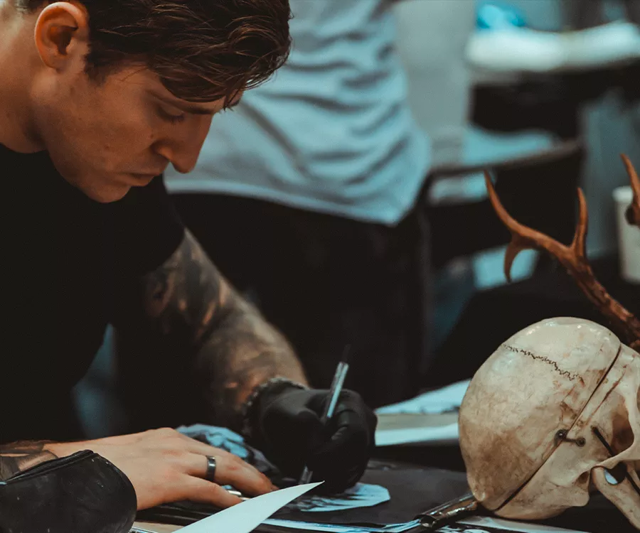 Fotografia eventowa prezentująca mężczyzne odrysowującego wzór tatuażu 