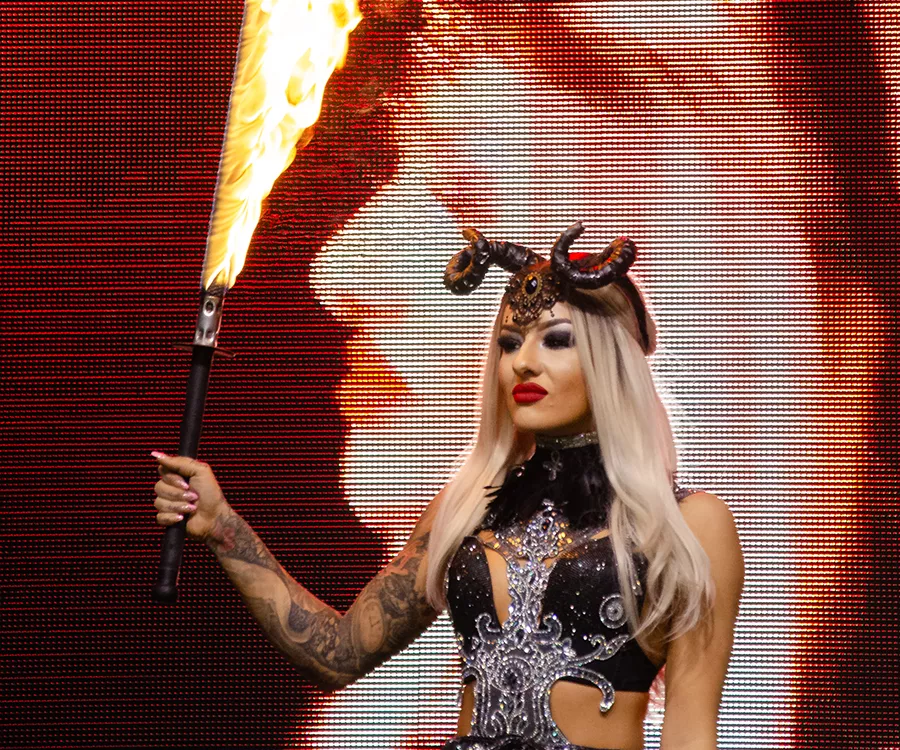 Fotografia eventowa prezentująca dziewczynę w stroju scenicznym, w dłoni trzyma płonący miecz, na głowie ma rogi.