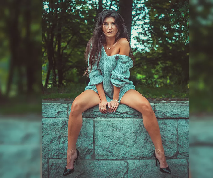 Portret dziewczyny siedzącej na murku, w tle park