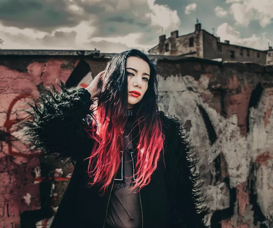 Alternatywnie wyglądająca dziewczyna na tle muru i rozpadajacych się budynków