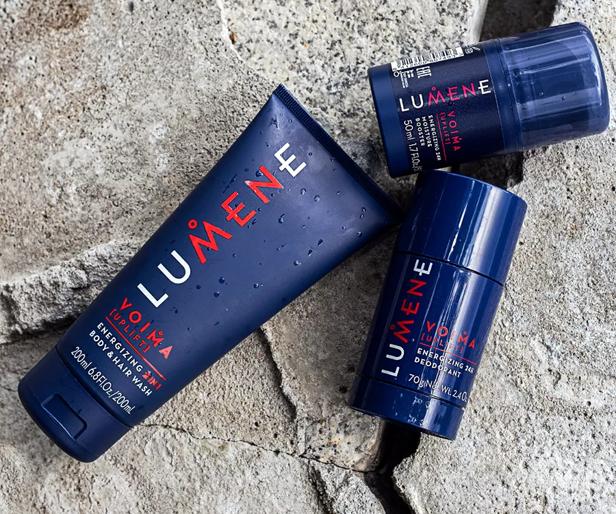 Zdjęcie produktowe przedstawiające męskie kosmetyki leżące na kamieniu i zraszone kroplami deszczu.