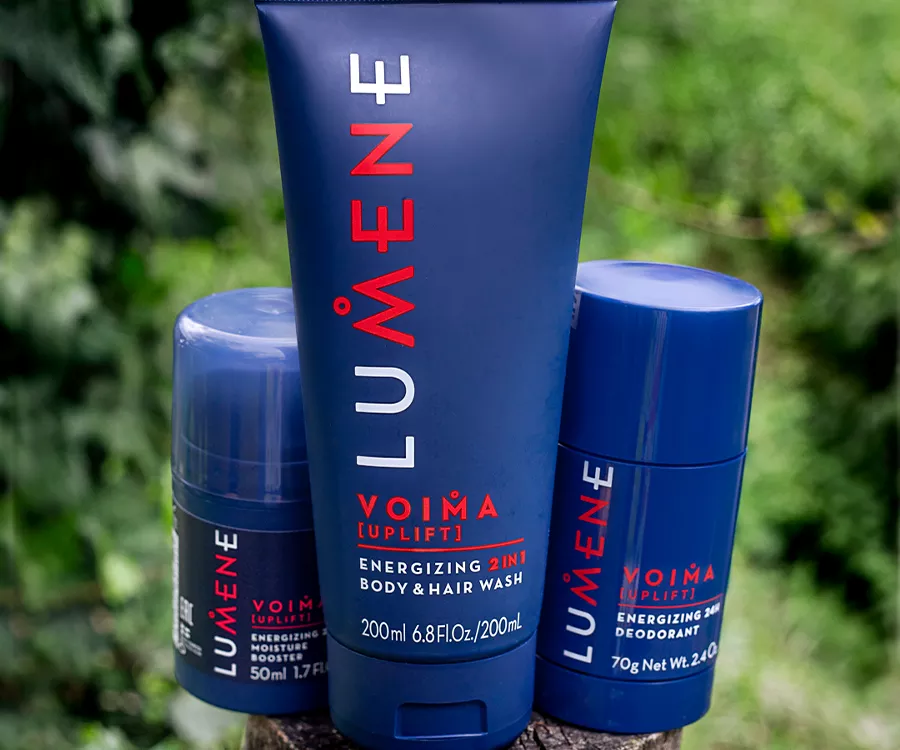 Zdjęcie produktowe przedstawiające męskie kosmetyki stojące na pniu. W tle jest rozmyta roślinność