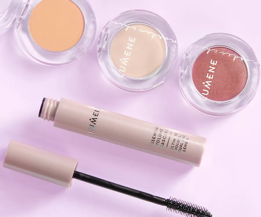 Zdjęcie produktowe przedstawiające mascare oraz szczoteczkę, wyżej znajdują się trzy małe, okrągłe, pojemniczki z różami do policzków