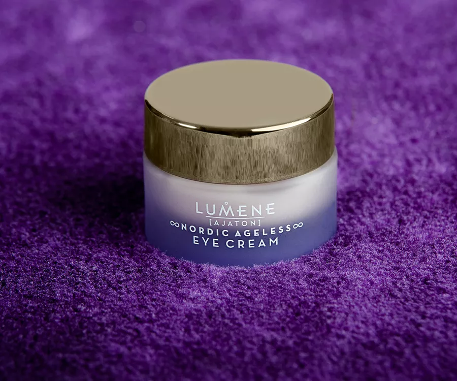 Zdjęcie produktowe przedstawiające fioletowy słoiczek z kremem pod oczy. Wykonany z mrożonego szkła, stoi na miękkim materiale w kolorze fioletowym