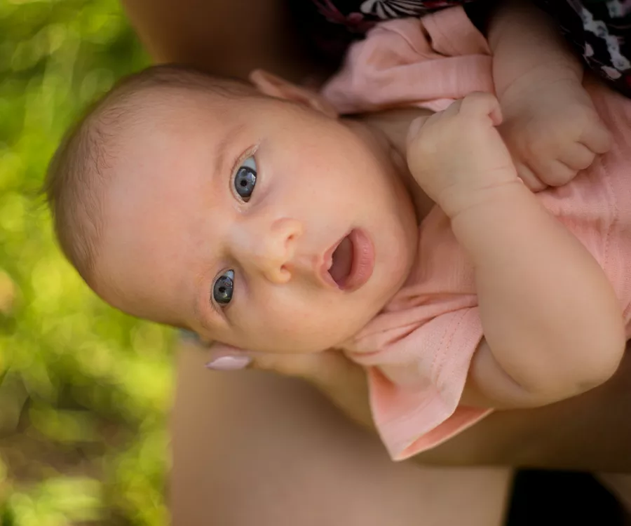 Fotografia rodzinna przedstawiająca kilku miesięczną dziewczynkę trzymaną przez mamę. 