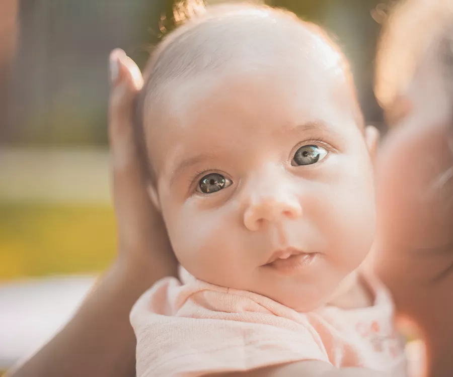 Fotografia rodzinna przedstawiająca kilku miesięczną dziewczynkę patrzącą wprost w obiektyw