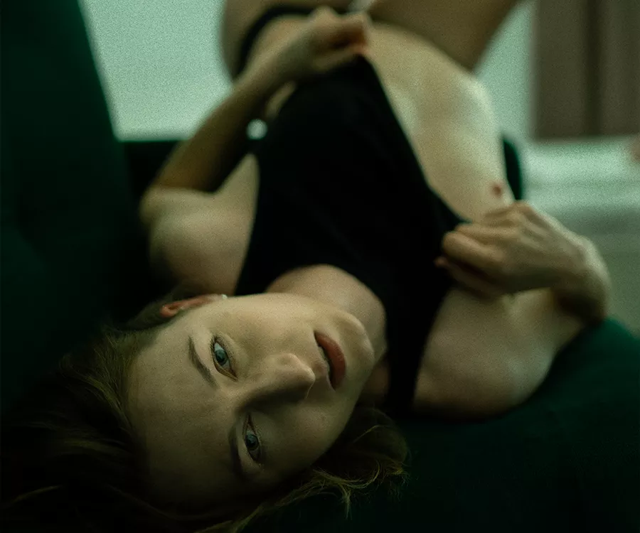 Fotografia dziewczyny w czarnej bieliźnie. Leżącej na wersalce. Odsłania pierś.