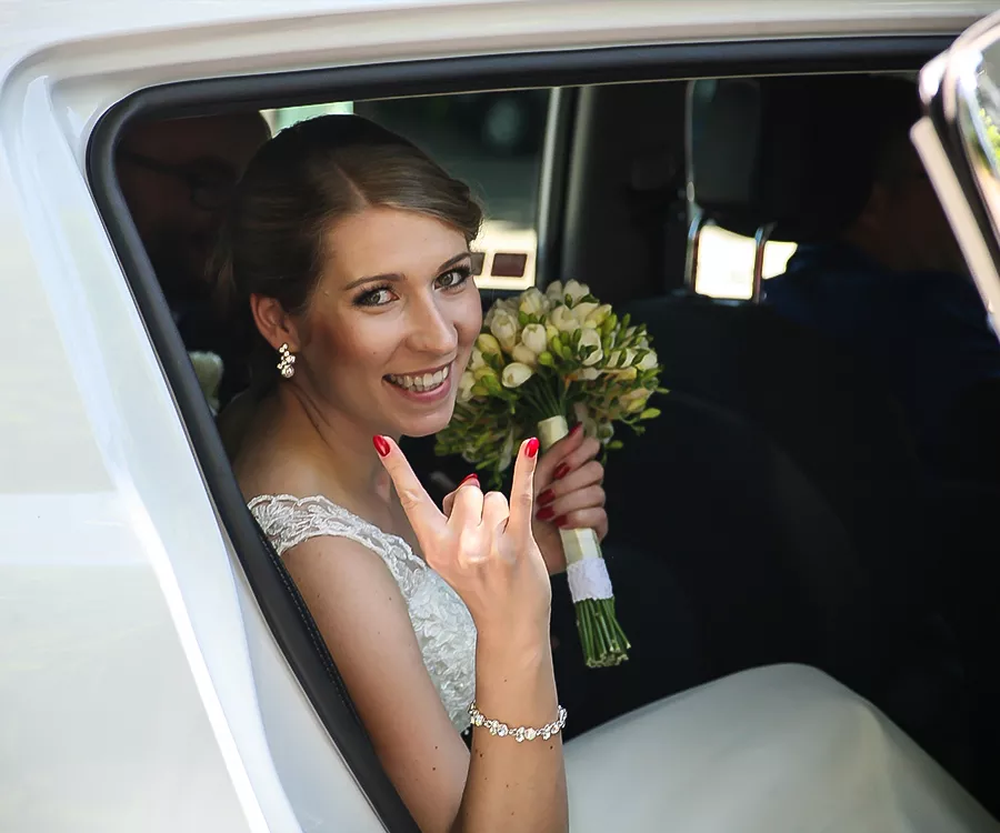 Zdjęcie panny młodej z bukietem kwiatów, siedzącej w samochodzie
