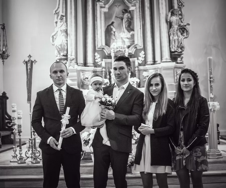 Zdjęcie rodziców z dzieckiem i chrzestnymi na tle ołtarza
