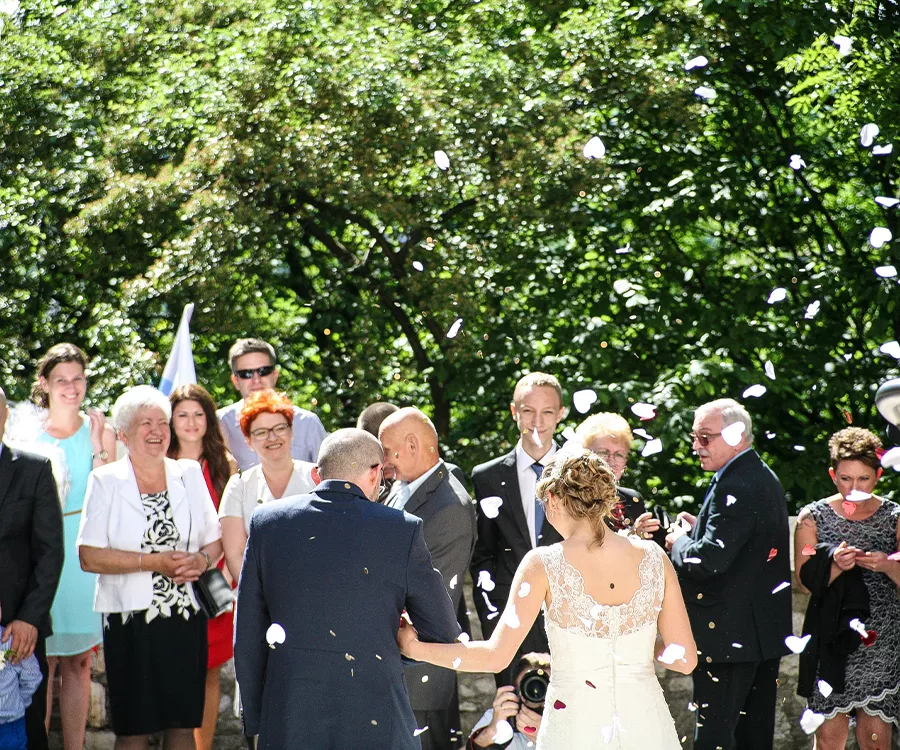 Zdjęcie pary młodej obsypywanej konfetii przez gości