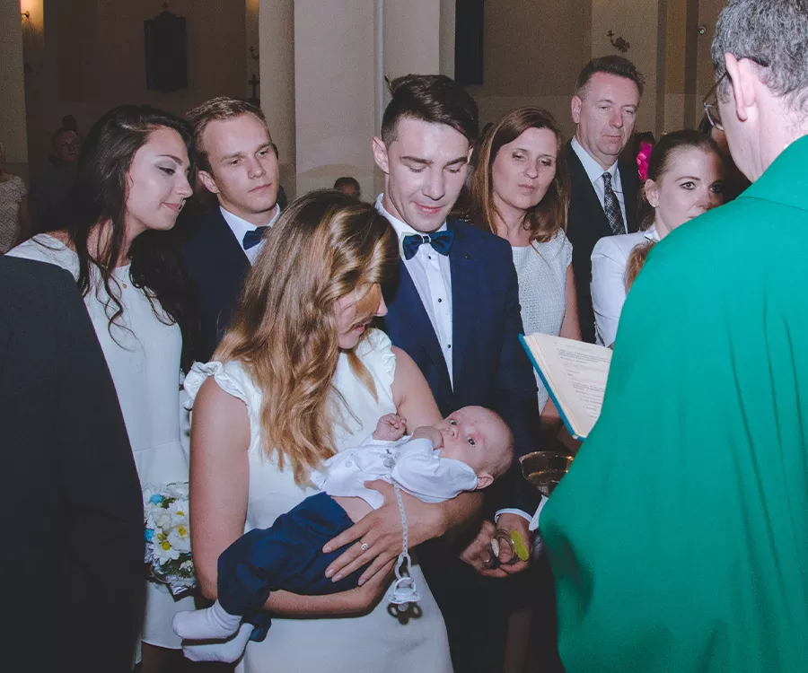 Mama trzymająca chłopca w trakcie chrztu